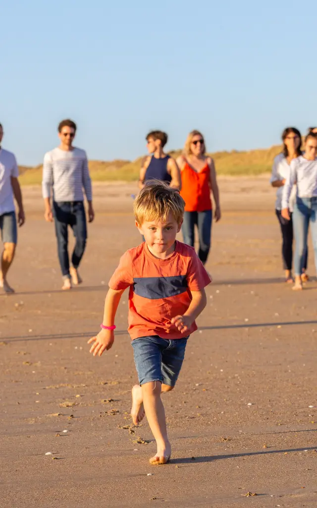 Un groupe d'enfants et d'adultes jouant avec un ballon sur une plage de sable