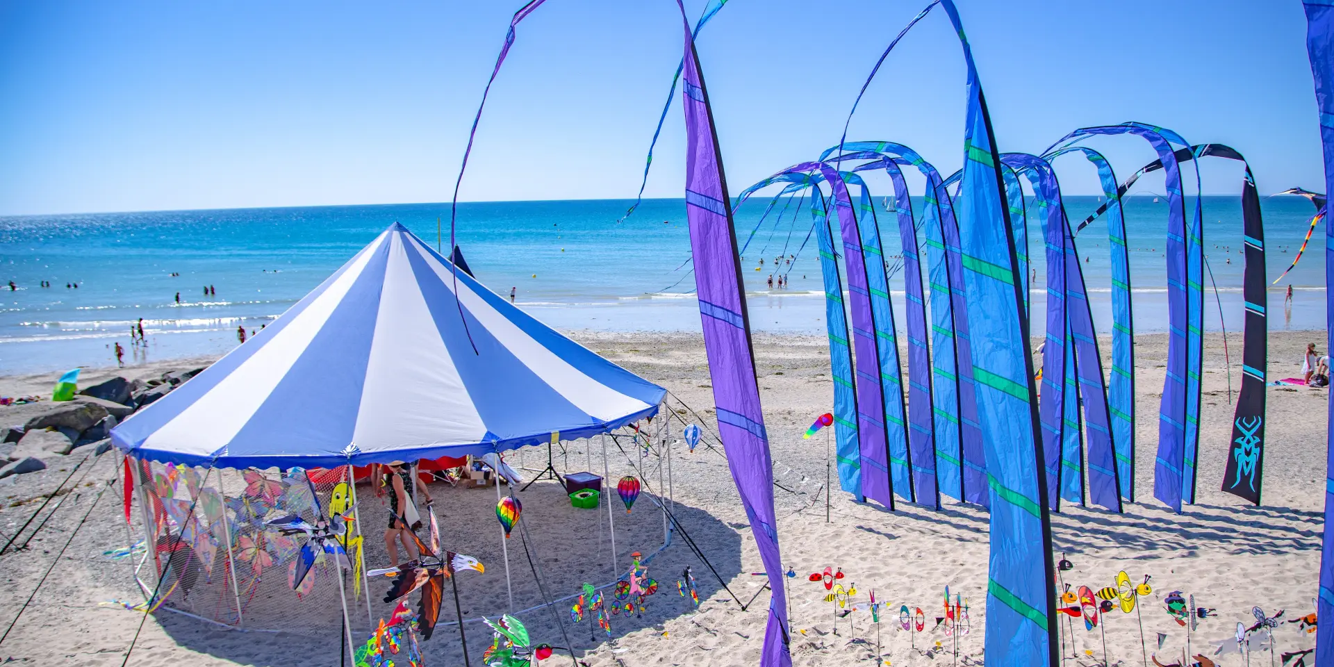 Kite festival with colorful kites and a blue tent on a beach