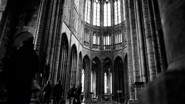 Menschen gehen in einer gotischen Kathedrale mit Bleiglasfenstern und hohen Säulen
