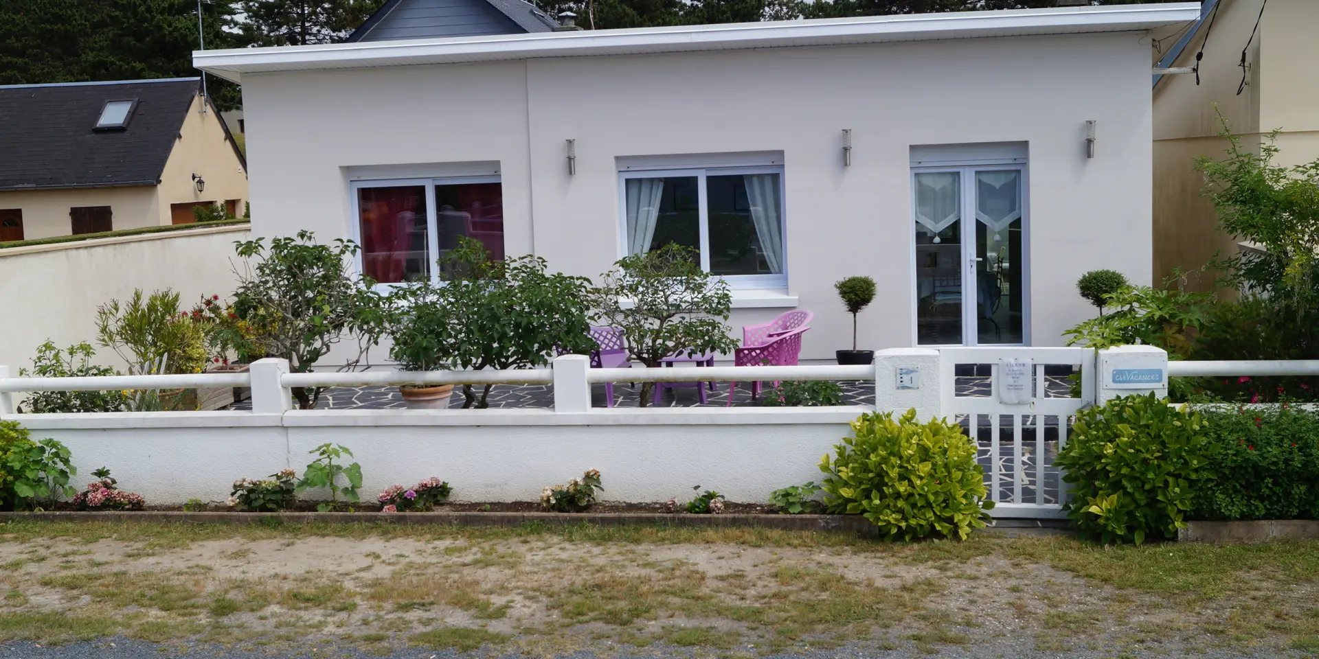 Weißes Haus mit Blumen Garten und weißem Zaun