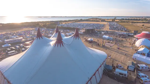 Luftaufnahme eines Festivals mit großen weißen Zelten und Besuchern