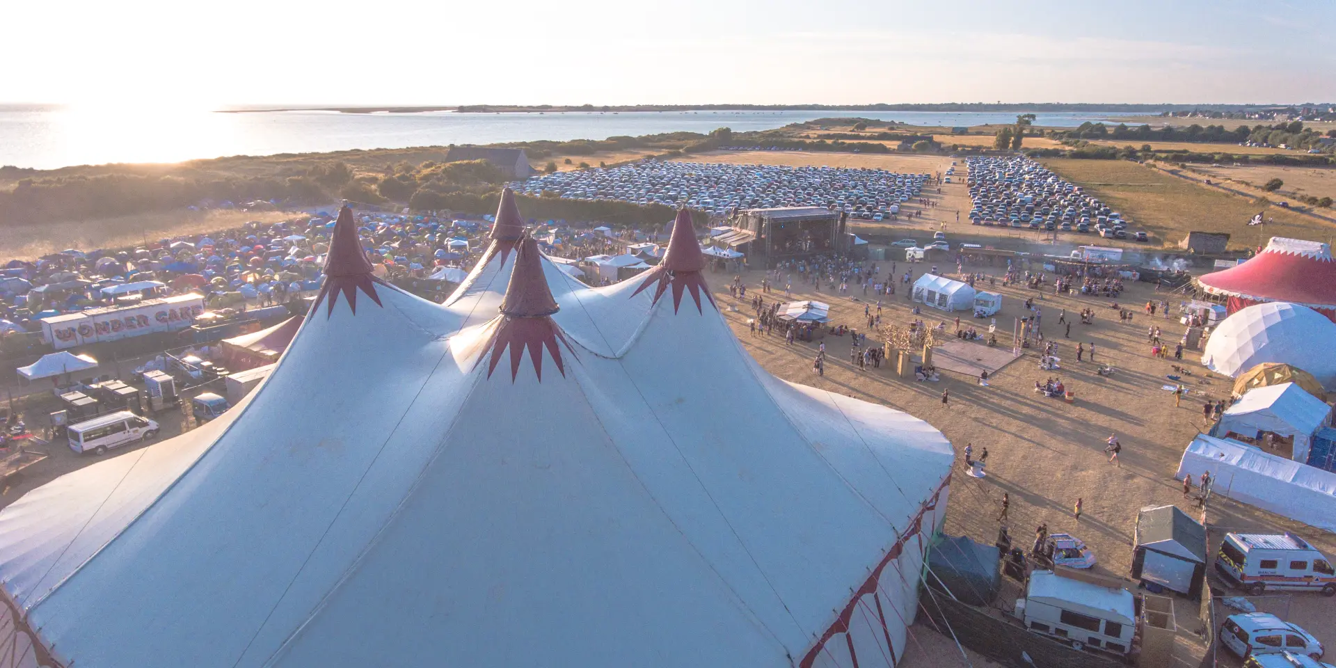 Luftaufnahme eines Festivals mit großen weißen Zelten und Besuchern