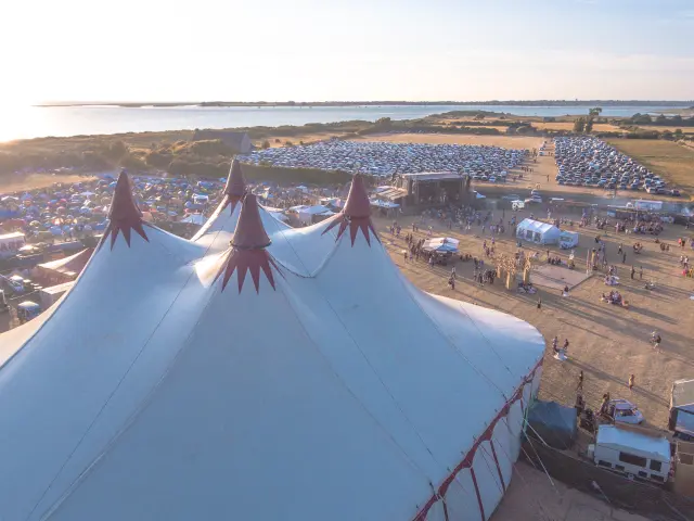 Luftaufnahme eines Festivals mit großen weißen Zelten und Besuchern