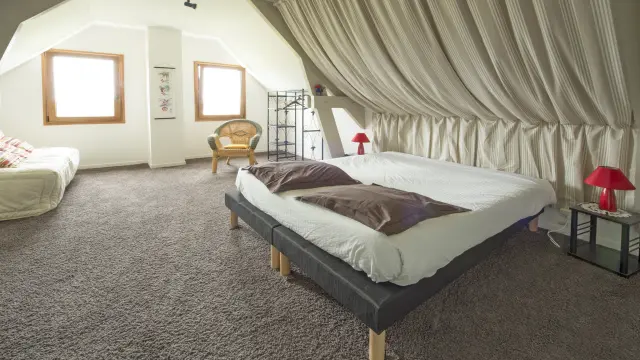 Attic bedroom with two beds, white curtains, and minimalist decor
