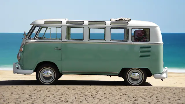 Ein vintage-grünes und weißes Wohnmobil auf einem Sandstrand