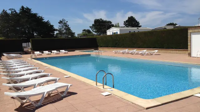 Rectangular pool with white lounge chairs lined up around it