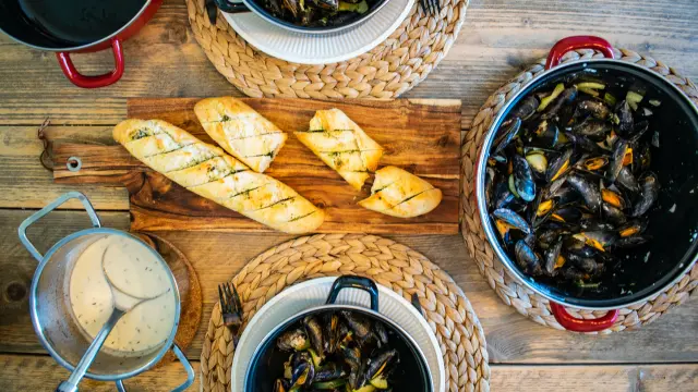 Un repas de fruits de mer avec des moules, du pain grillé et une sauce blanche