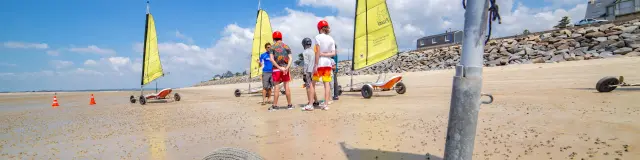 Group of people learning to use land sailers on a beach