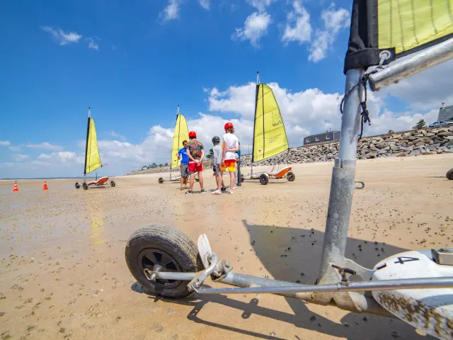 Group of people learning to use land sailers on a beach