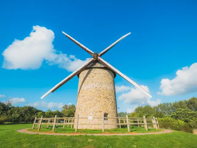 Eine Steinwindmühle mit Holzblaettern unter einem klaren blauen Himmel