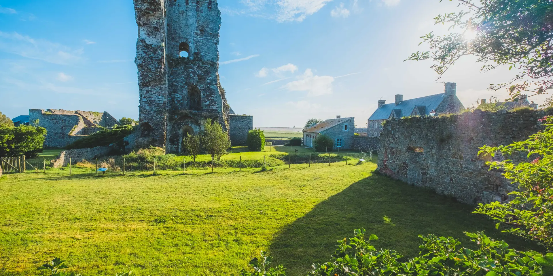 Ruins of a medieval castle with stone walls and modern buildings nearby