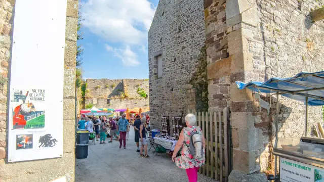 A stone archway with people walking through and market stalls on either side