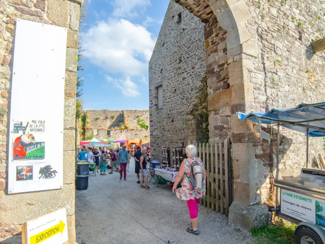 A stone archway with people walking through and market stalls on either side