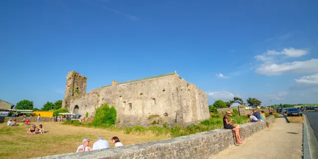 Ruins of a medieval castle with people sitting on a stone wall