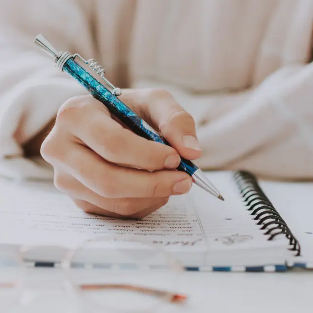 Main tenant un stylo bleu sur un cahier