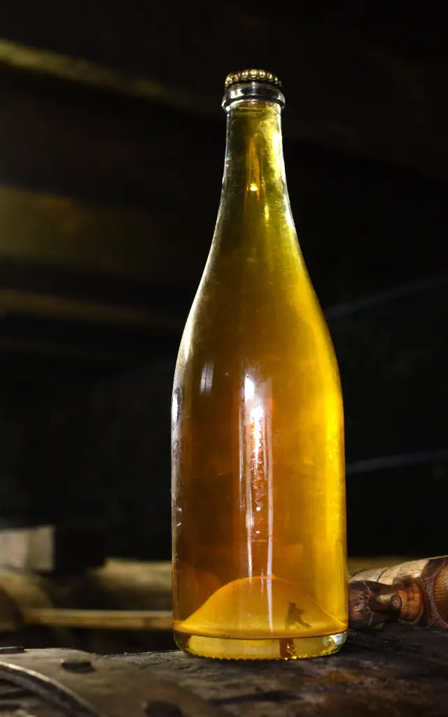 Deux bouteilles de cidre artisanal sur un tonneau en bois