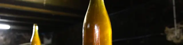 Deux bouteilles de cidre artisanal sur un tonneau en bois