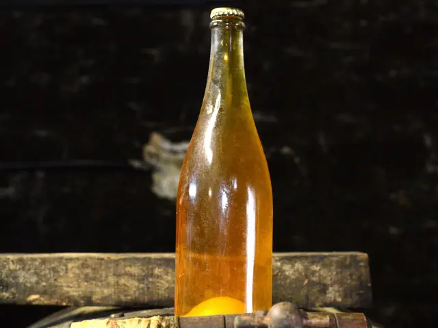 Bouteille de cidre posée sur un tonneau en bois