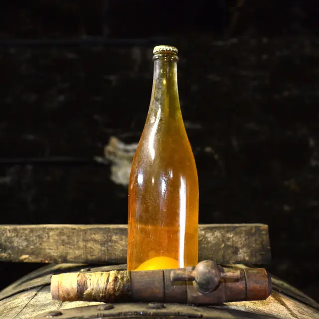 Bouteille de cidre posée sur un tonneau en bois