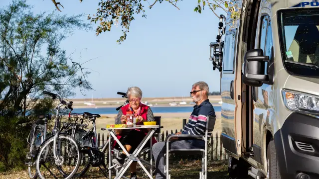 Deux personnes pique-niquent devant un camping-car
