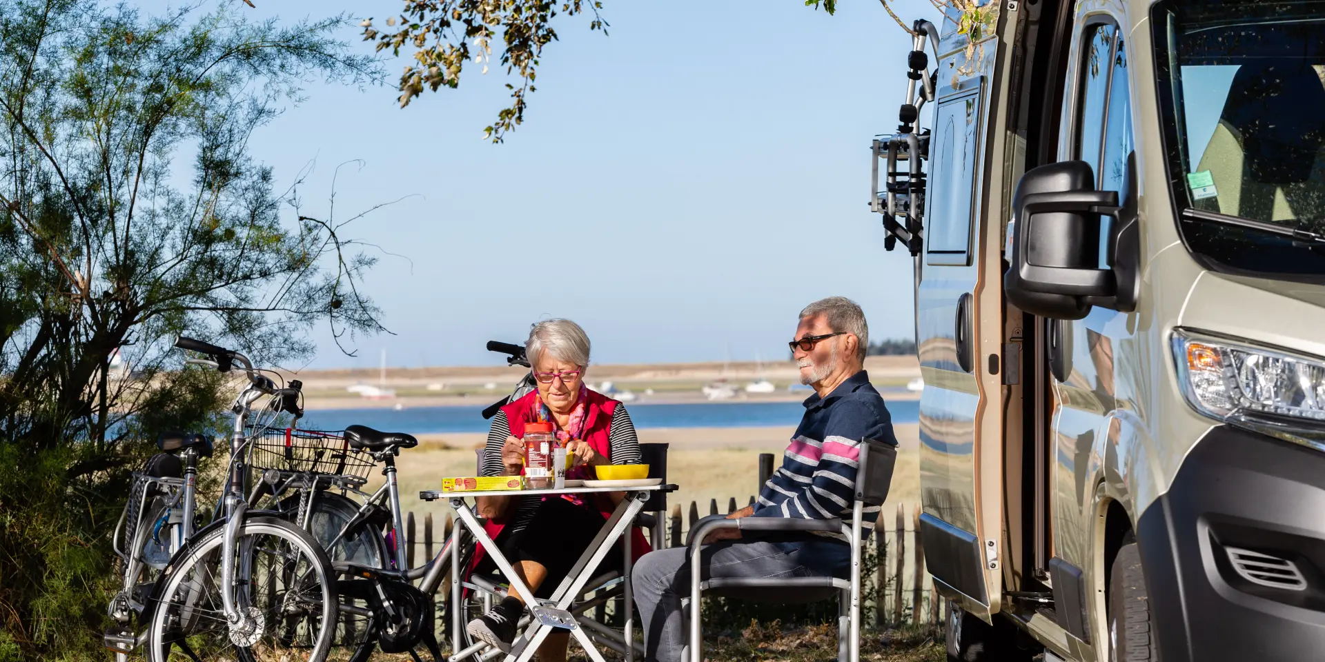 Deux personnes pique-niquent devant un camping-car