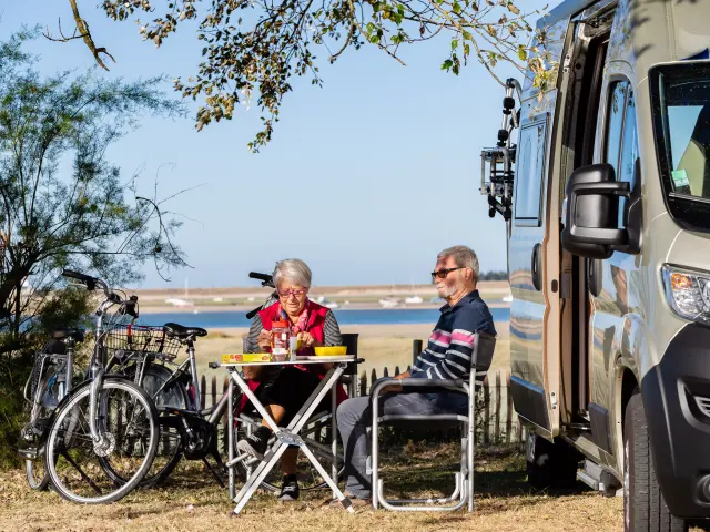 Deux personnes pique-niquent devant un camping-car