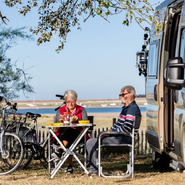Deux personnes pique-niquent devant un camping-car