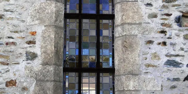 Fenêtre gothique avec vitrail coloré dans un mur de pierre de l'Ermitage Saint Gerbold