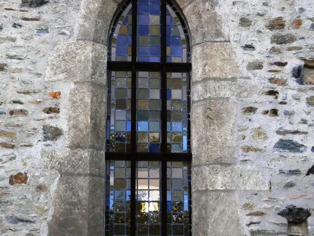 Gothic window with colorful stained glass in a stone wall