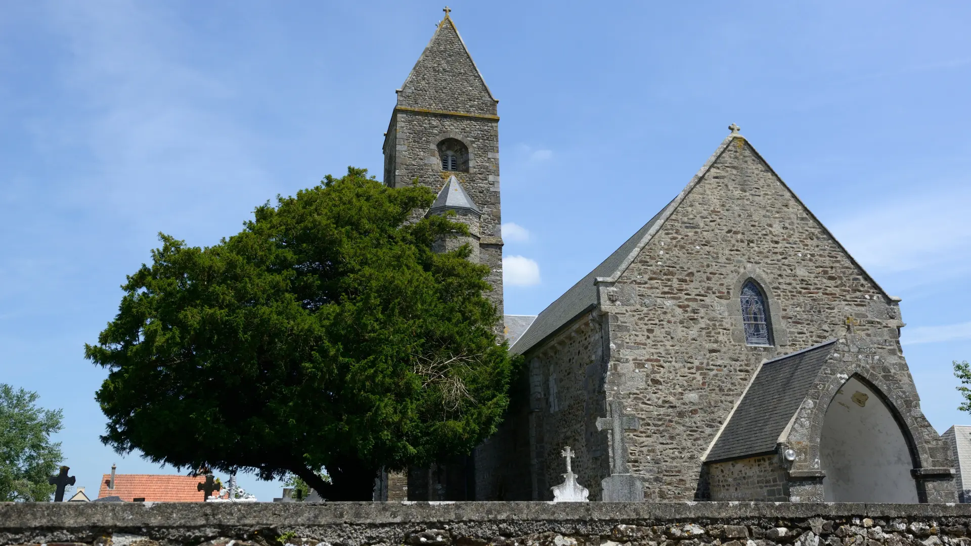 Steinkirche mit einem Glockenturm und einem Baum links