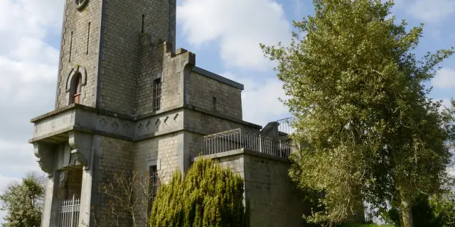 Stone tower with an arched entrance and surrounding trees