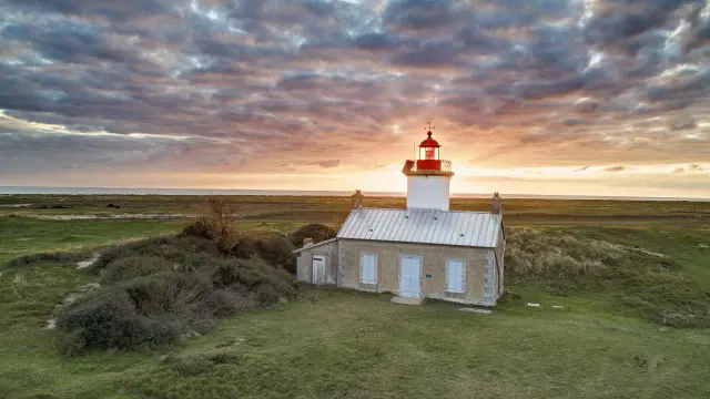 Einsamer Leuchtturm in einer grasbewachsenen Landschaft bei Sonnenuntergang
