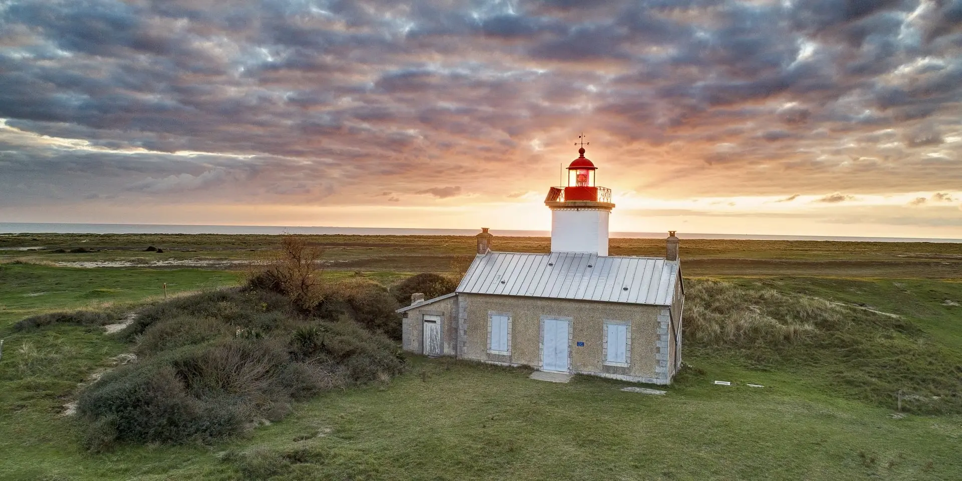Einsamer Leuchtturm in einer grasbewachsenen Landschaft bei Sonnenuntergang