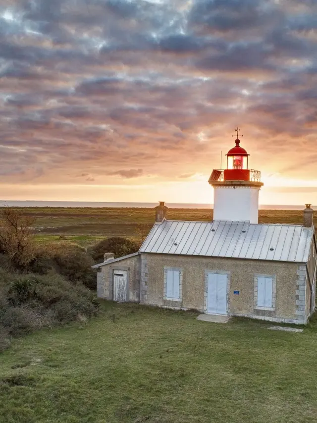 Isolated lighthouse in a grassy landscape at sunset