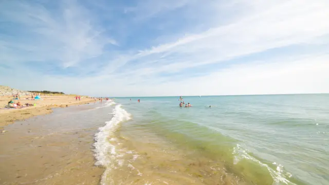 Menschen, die sich am Sandstrand sonnen und baden