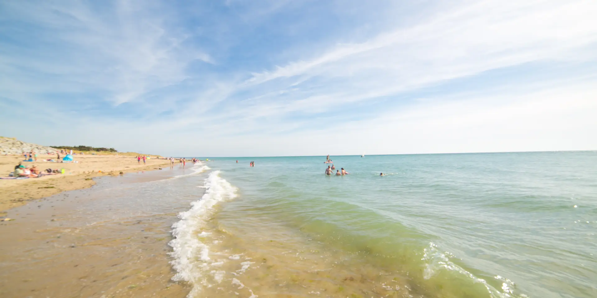 Menschen, die sich am Sandstrand sonnen und baden