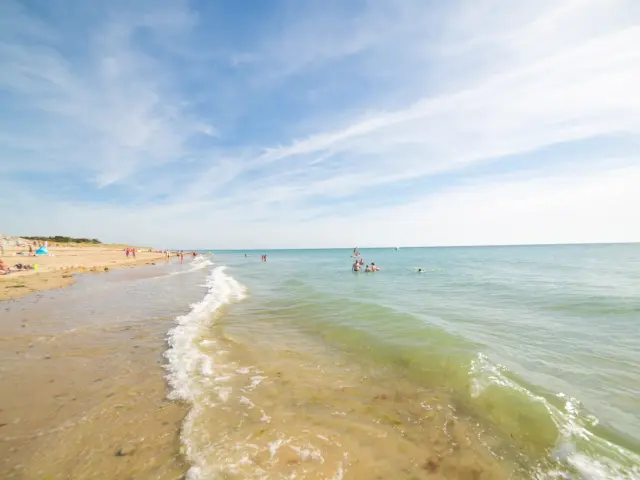 Menschen, die sich am Sandstrand sonnen und baden