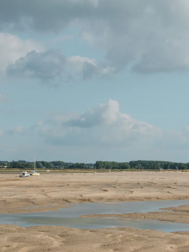 Sandstrand mit Wasserpfützen und bewölktem Himmel