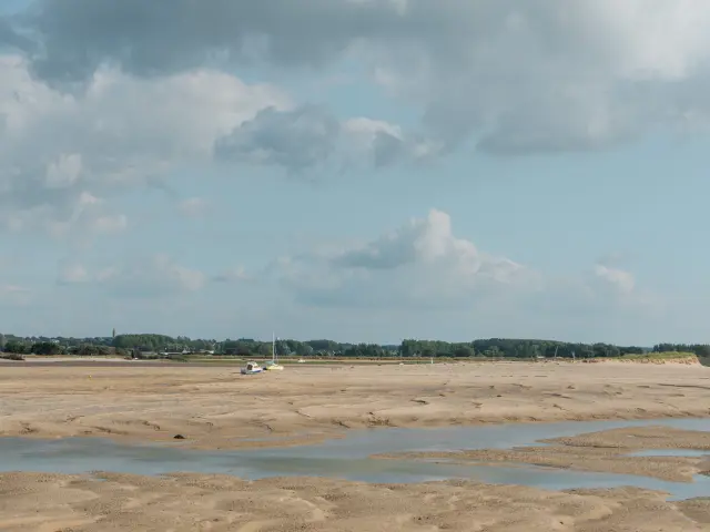 Sandstrand mit Wasserpfützen und bewölktem Himmel