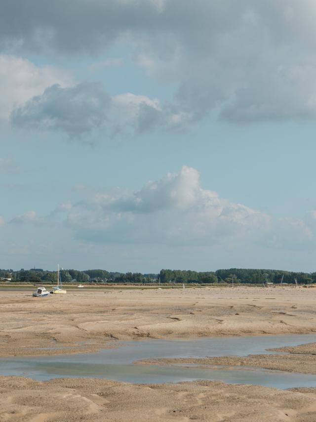 Sandy beach with water puddles and a cloudy sky