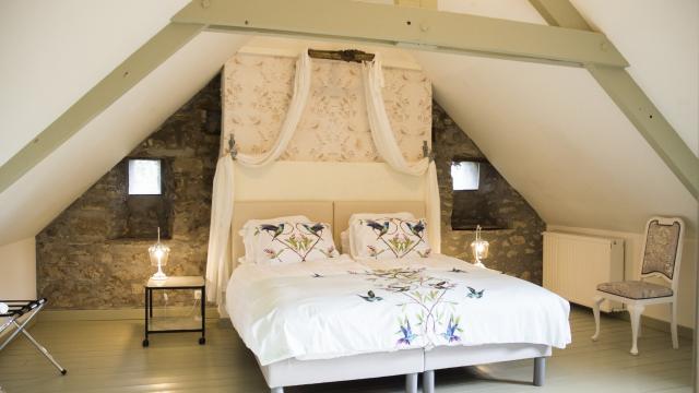 Chambre à coucher avec un grand lit à baldaquin et des murs en pierre apparente