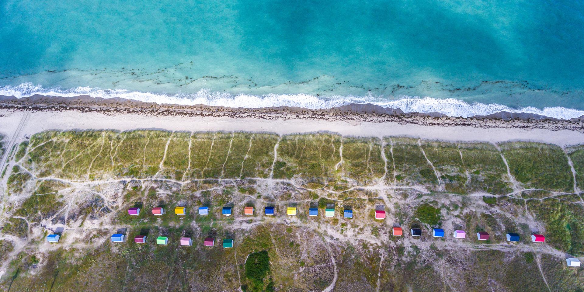 White sandy beach with colorful beach huts and turquoise sea