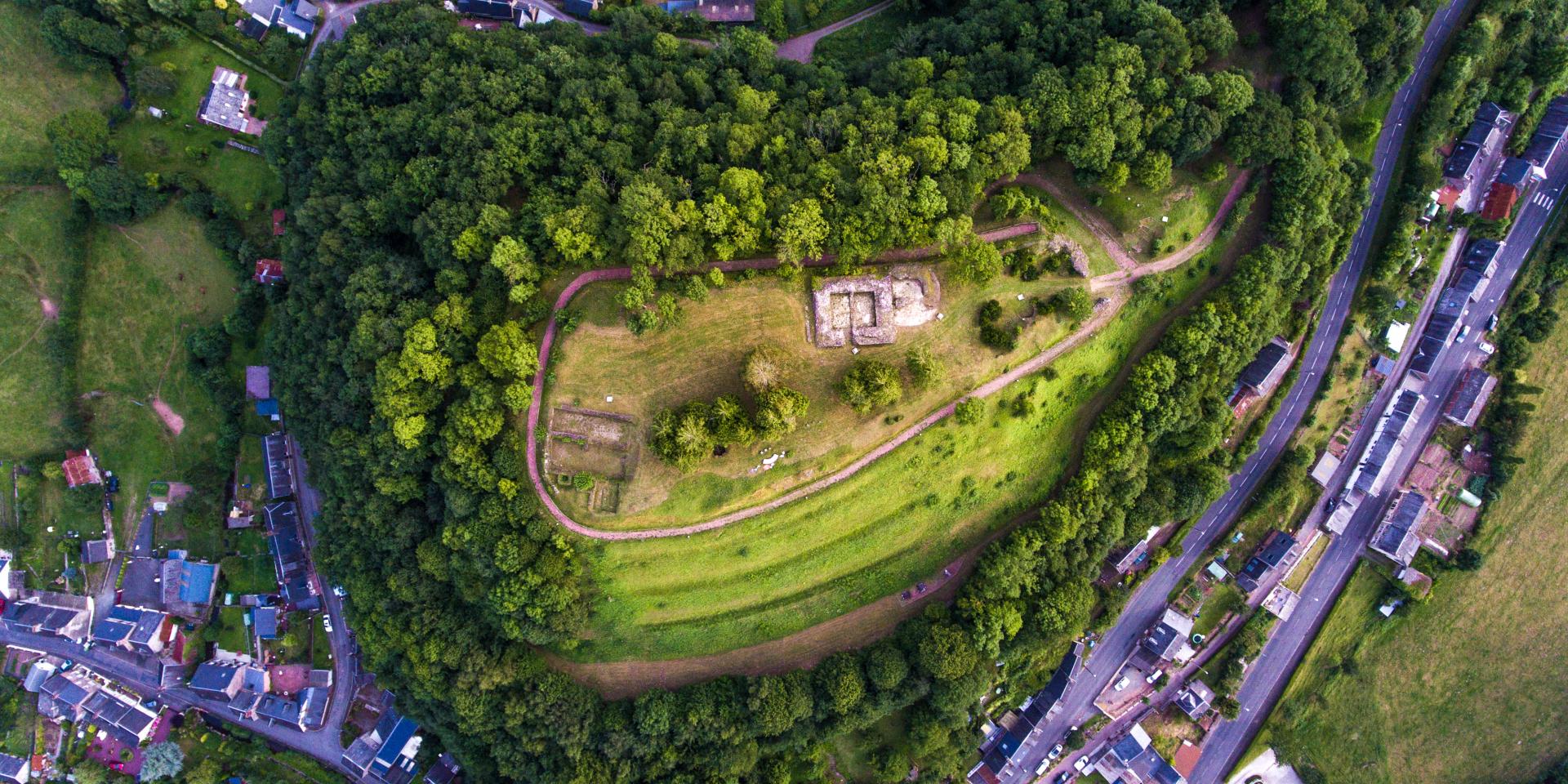 Vue aérienne d'une colline boisée avec des sentiers et des structures en pierre