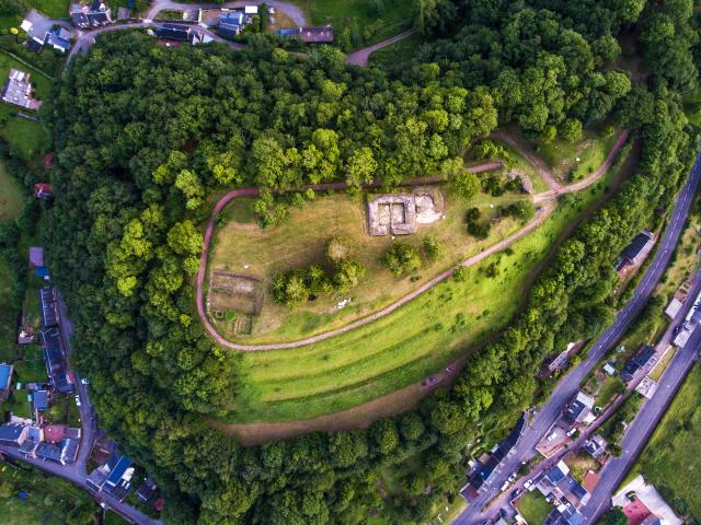 Vue aérienne d'une colline boisée avec des sentiers et des structures en pierre