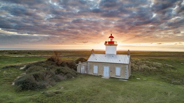 Einsamer Leuchtturm in einer grasbewachsenen Landschaft bei Sonnenuntergang
