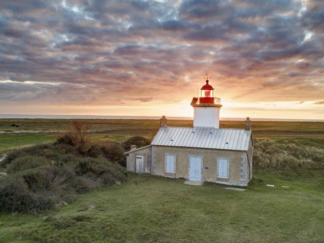 Isolated lighthouse in a grassy landscape at sunset
