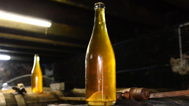 Deux bouteilles de cidre artisanal sur un tonneau en bois