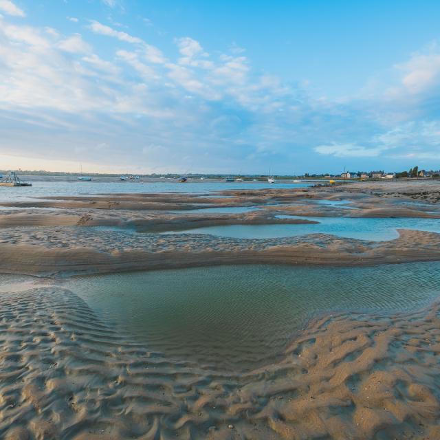 Marée basse sur une plage avec des flaques d'eau et des traces de pas