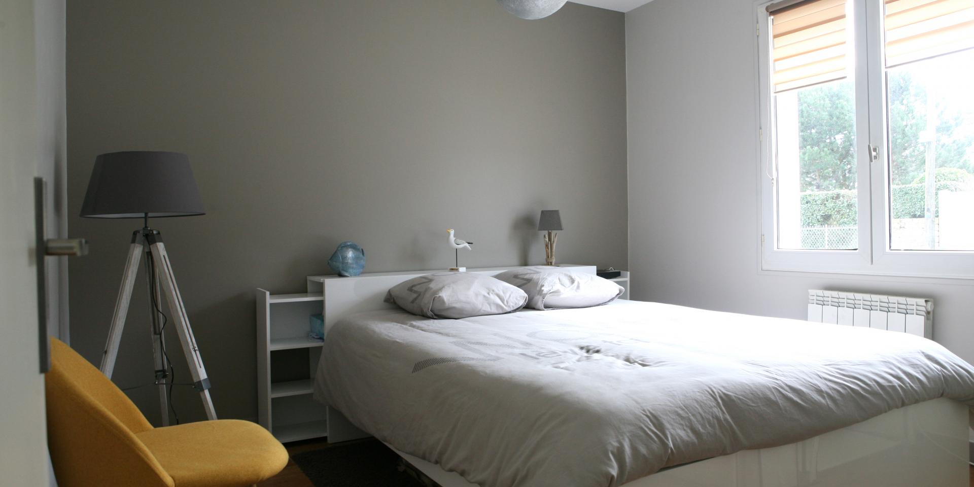 Bedroom with a white bed, a yellow chair, a floor lamp, and a window with blinds