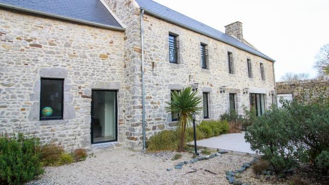 Stone house with large windows and landscaped garden